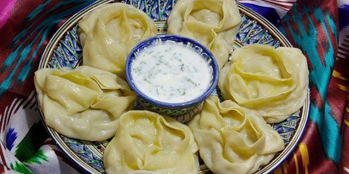 Готовые манты с соусом на тарелке